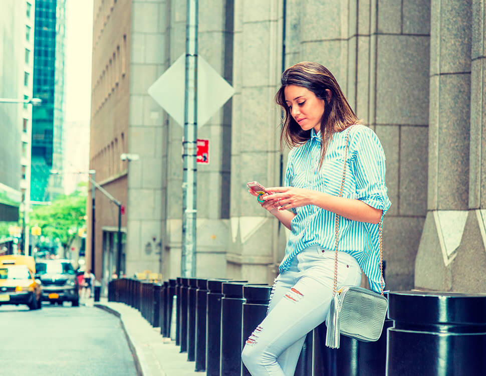 Mulher que está na rua digitando em um smartphone